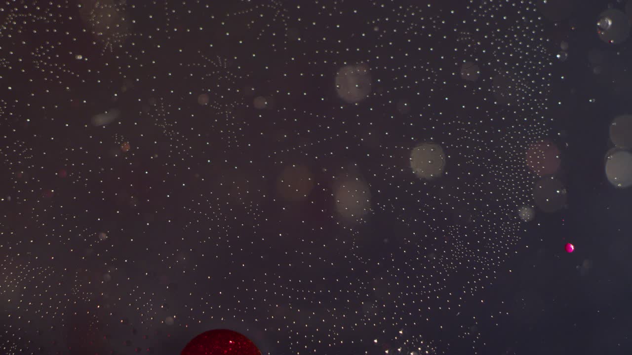 Abstract red and clear orbs moving together in clear liquid bokeh texture background