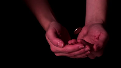 money dropping into hands on black background