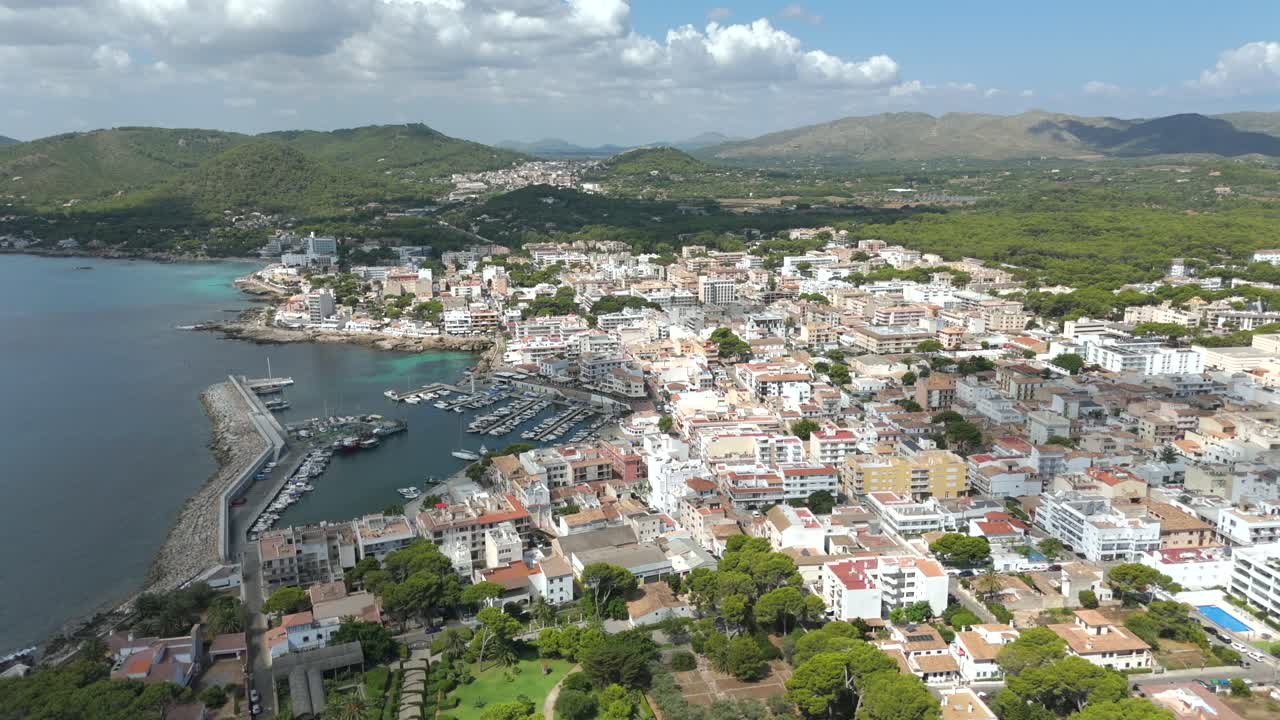 Aerial pan across seaside town and harbor in Majorca, Spain on sunny day