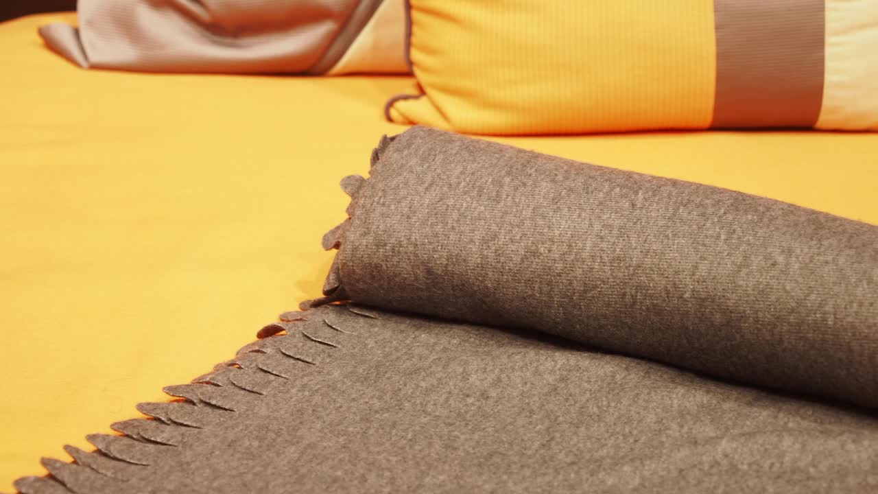 오렌지색 침대 위에 회색 담요가 휘어져 있습니다.