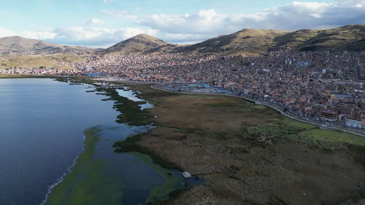 Aerial ascends over Lake Titicaca shoreline pier harbour in Puno, Peru