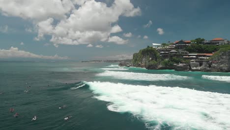drone view of lots of people doing surf in the south coast of bali waiting to catch the perfect wave