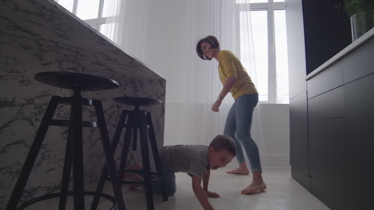 Happy mom with a child playing catch-up in the house in a bright apartment. Run around the house laughing and smiling. Playing tag with my son. Play hide and seek
