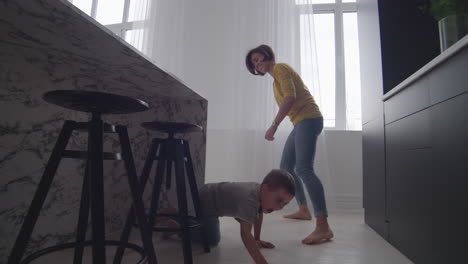 Mamá-Feliz-Con-Un-Niño-Jugando-A-Ponerse-Al-Día-En-La-Casa-En-Un-Apartamento-Luminoso.-Corre-Por-La-Casa-Riendo-Y-Sonriendo.-Jugando-A-La-Mancha-Con-Mi-Hijo.-Jugar-A-Las-Escondidas