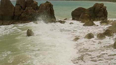 Slow-motion-shot-of-waves-crashing-into-the-rocky-coastline-of-Banbanon-Beach,-Surigao-Del-Norte,-Philippines-on-a-cloudy-day