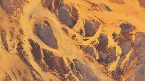 abstract drone view over þjórsá river delta in iceland, golden volcanic sediment and braided channels form surreal natural patterns.