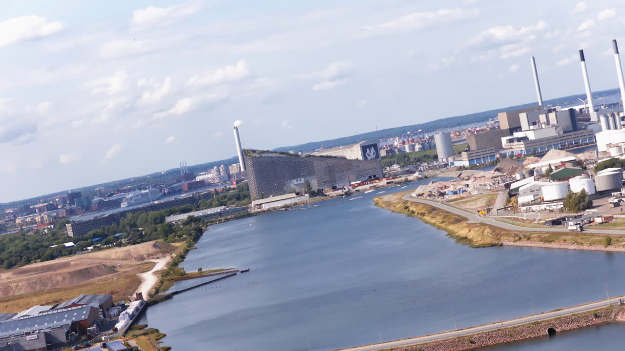 Aerial drone view of the coastline near Amager Strandpark, with sailboats in the water and CopenHill visible in the distance in Copenhagen, Denmark