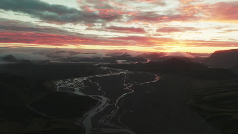 Aerial-view-of-vibrant-sunrise-over-foggy-Landmannalaugar-Valley,-establishing-shot