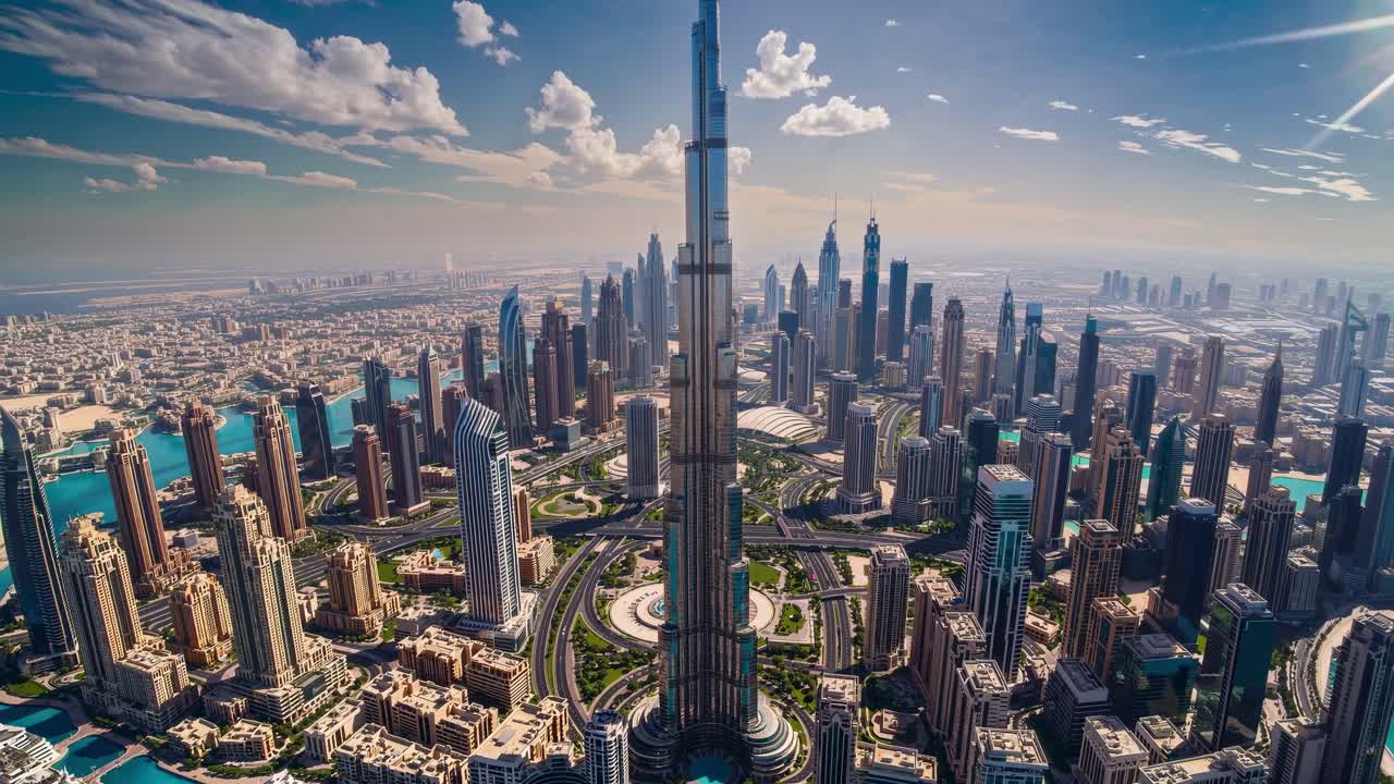 uma vista aérea de tirar o fôlego de uma metrópole moderna com um proeminente arranha-céu em seu centro, cercada por uma densa rede de edifícios, estradas e cursos de água sob um céu ensolarado brilhante