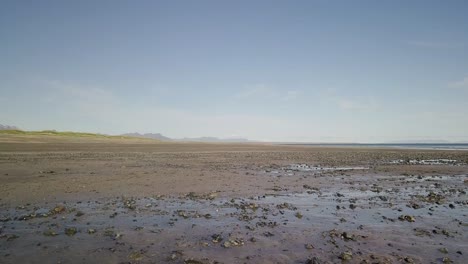 Vuelo-Bajo-Sobre-Una-Playa-Rocosa-Y-El-Océano-Bajo-El-Sol-Durante-El-Verano-Soleado-En-La-Península-De-Snaefellsness,-Islandia