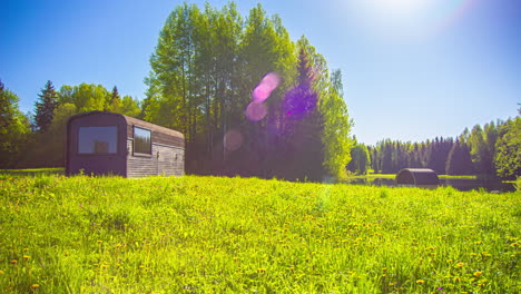 Fusion-clip-of-a-small-wooden-cottage-on-a-beautiful-spring-landscape-and-colorful-sky-during-sunrise-and-sunset---Fir-trees,-green-grass-and-wooden-cottage