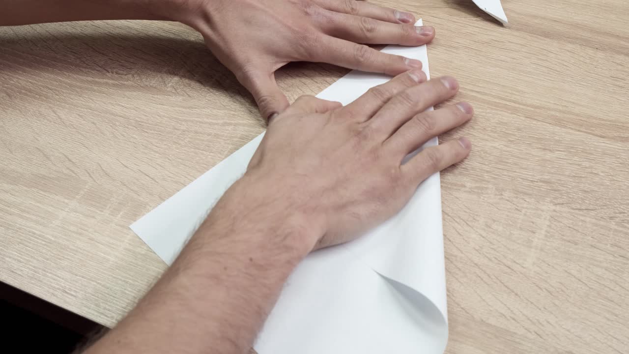 persona doblando un avión de papel