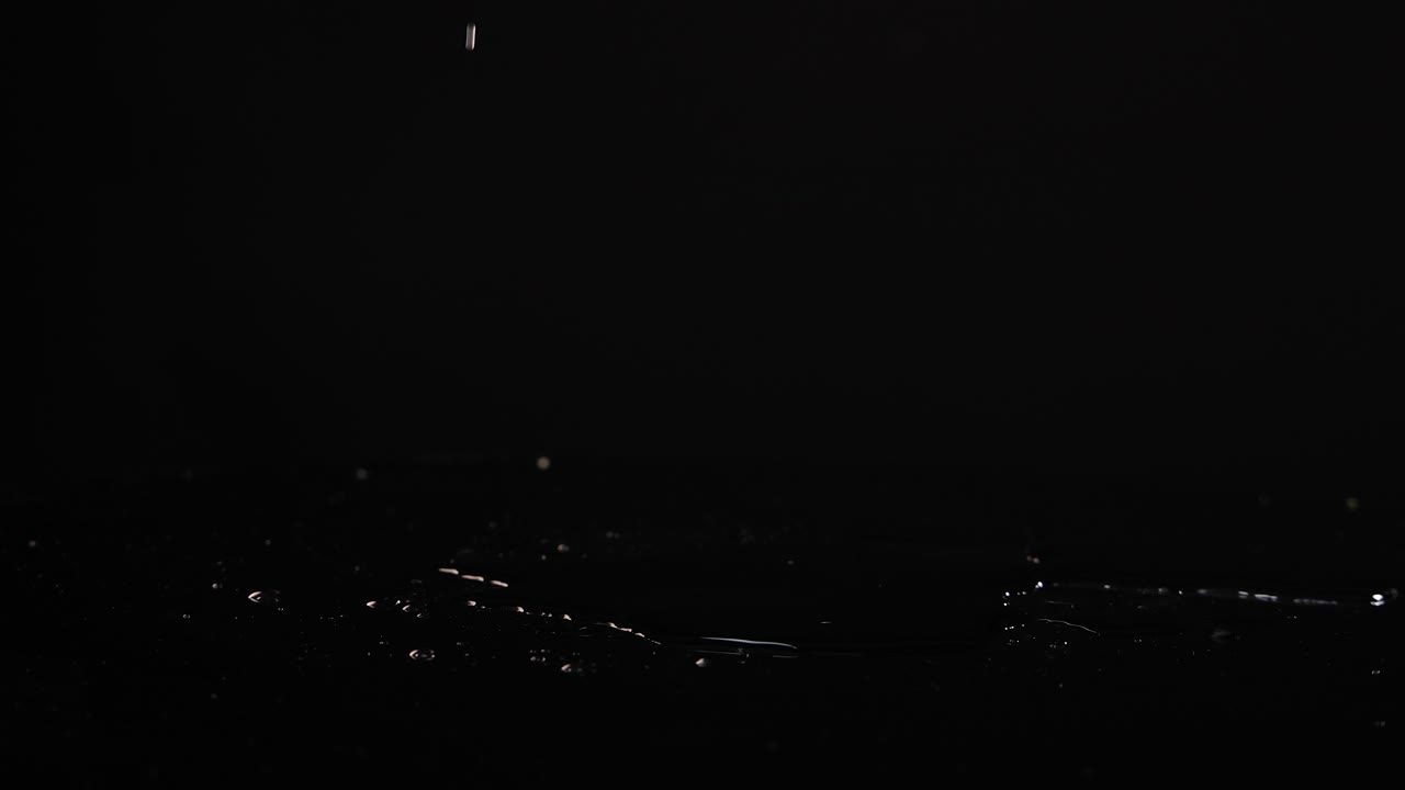 Lemon slices fall and settle on a reflective black surface, captured in slow motion with dramatic lighting