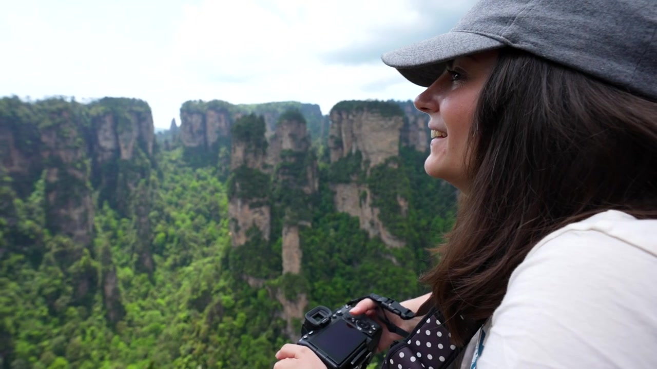 Wisatawan wanita tersenyum dengan kamera menikmati pemandangan gunung yang menakjubkan di Yuanjiajie.