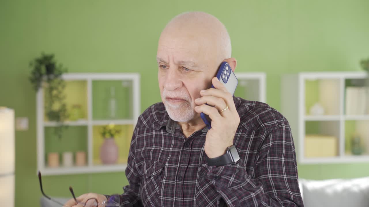 Elderly man talking on the phone at home angry and aggressive.