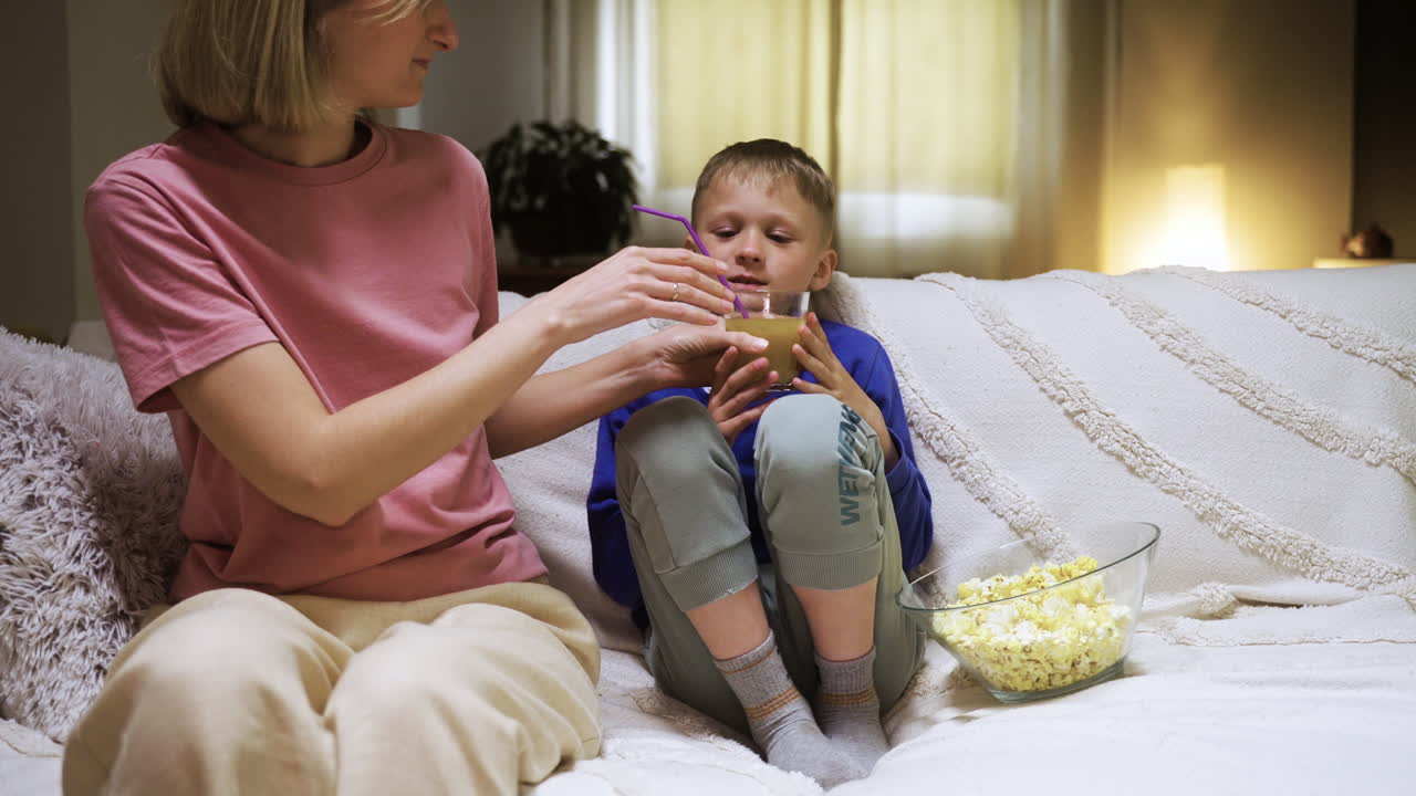 Bambino che guarda la TV e beve succo