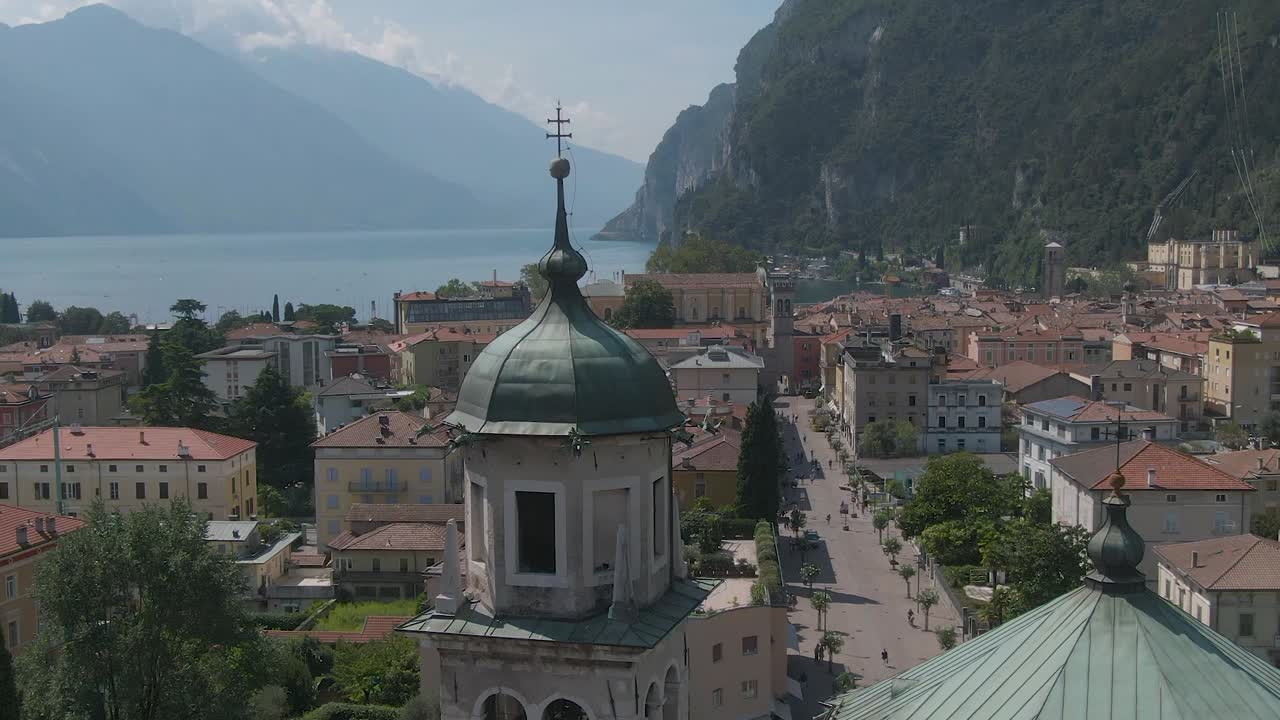 리바 델 가다 (riva del garda) 의 중심에 있는 교회, 그 배경에는 이탈리아의 알프스 산맥과 가다 호수 (lake garda) 가 있다.