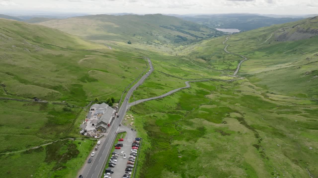 Kirkstone Pass Busy Summit With Full Car Park And View Down To Lake Windermere. Summer., Lake District, Cumbria, UK