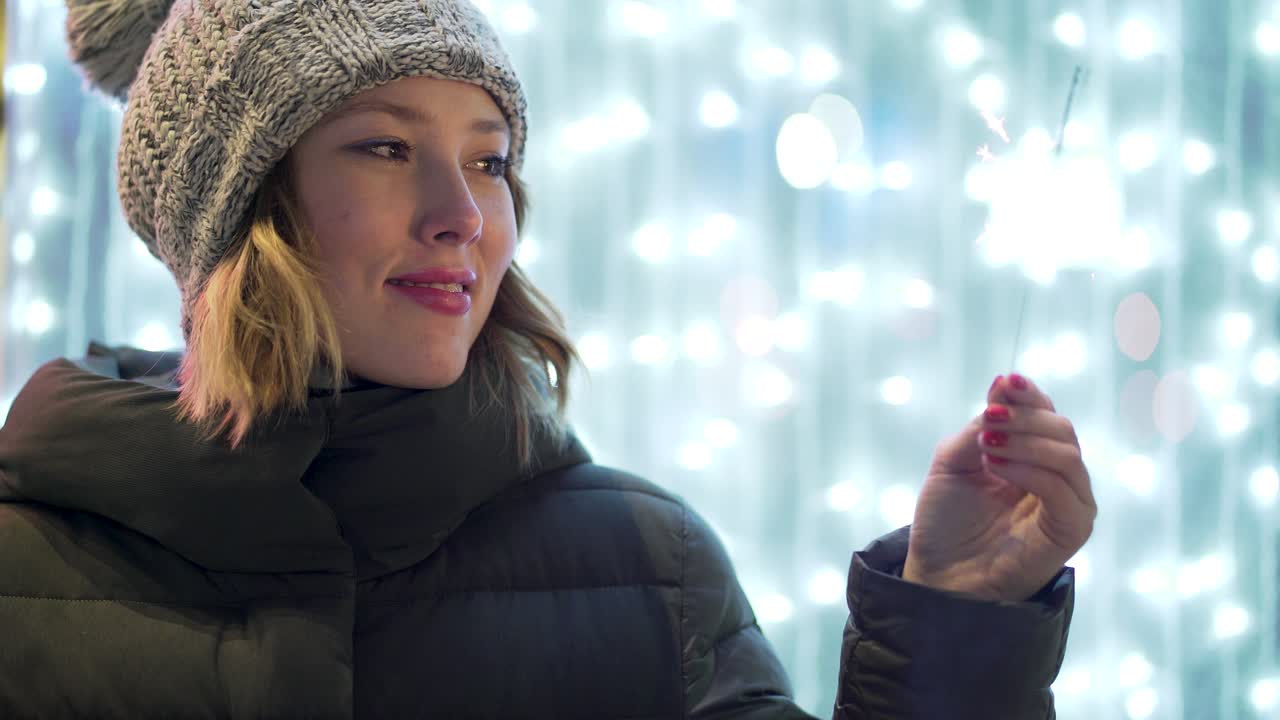 축제 조명 앞에 반이는 불꽃을 들고 있는 여자