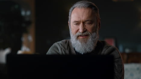 Bearded-old-man-having-video-call-on-computer-indoors