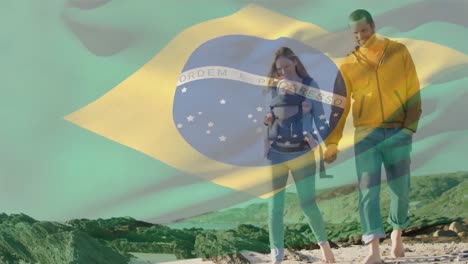 Animation-of-waving-brazil-flag-against-caucasian-couple-with-a-baby-walking-on-the-beach