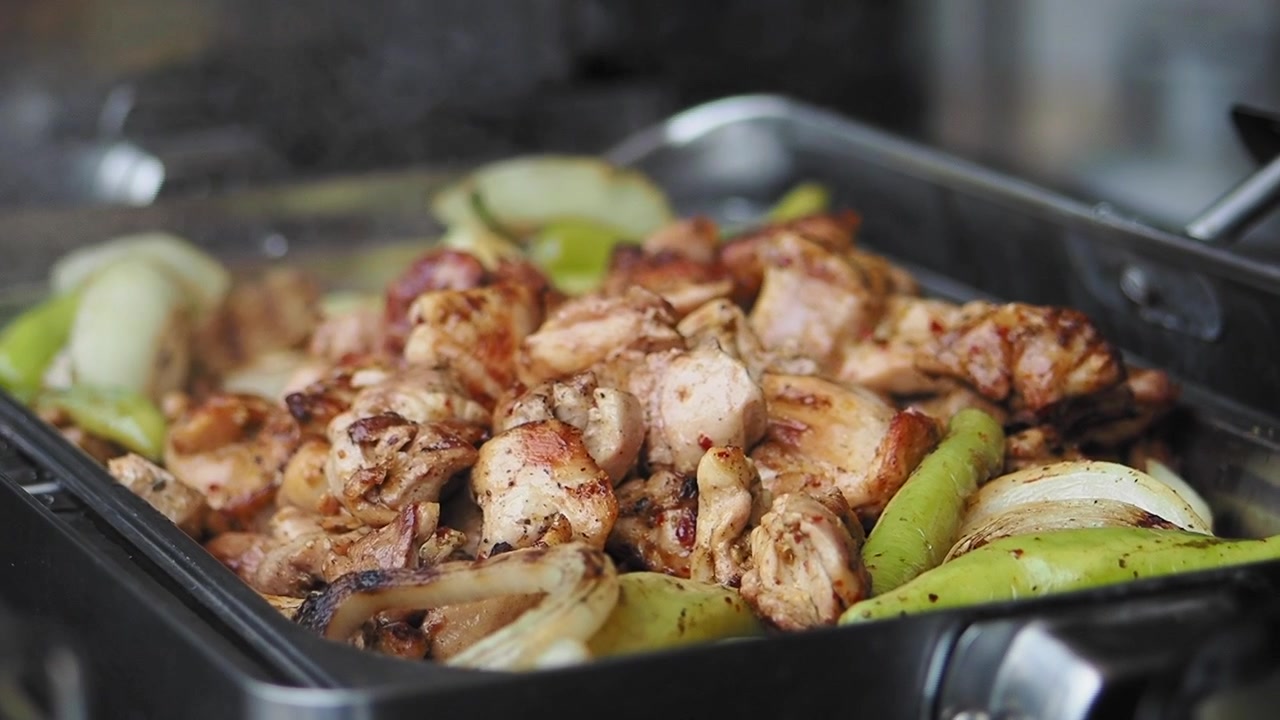 Pollo e verdure che sfrigolano su una griglia calda