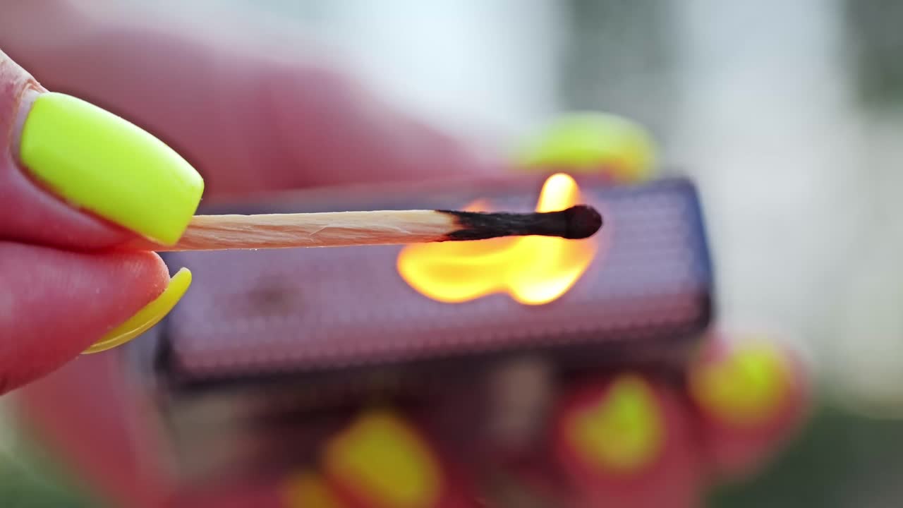 Macro shot of wooden match lighting up with clean orange flame in slow motion