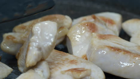 pieces of chicken meat are fried and turned over in a pan