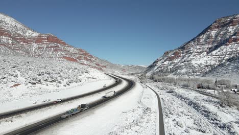 下面是沿着i-70在山上开车的半拖拉机拖拉机,地上有新鲜的雪