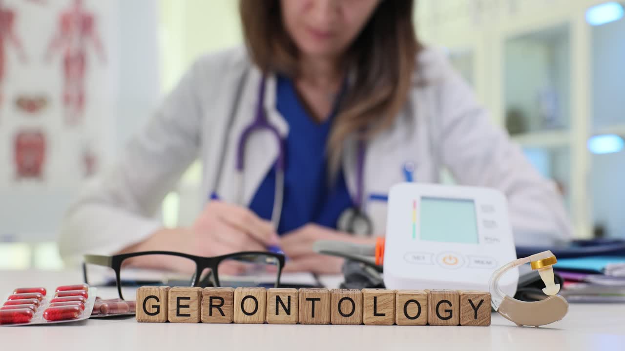 Palavra 'Gerontologia' na mesa com médico trabalhando em consultório médico