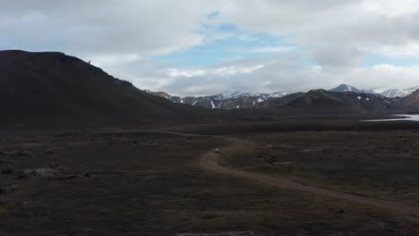High-angle-view-panorama-of-4x4-vehicle-driving-offroad-stony-terrain-exploring-wilderness-of-icelandic-highlands.-Top-view-Skaftafell-national-park-with-snowy-mountains-and-green-moss-countryside