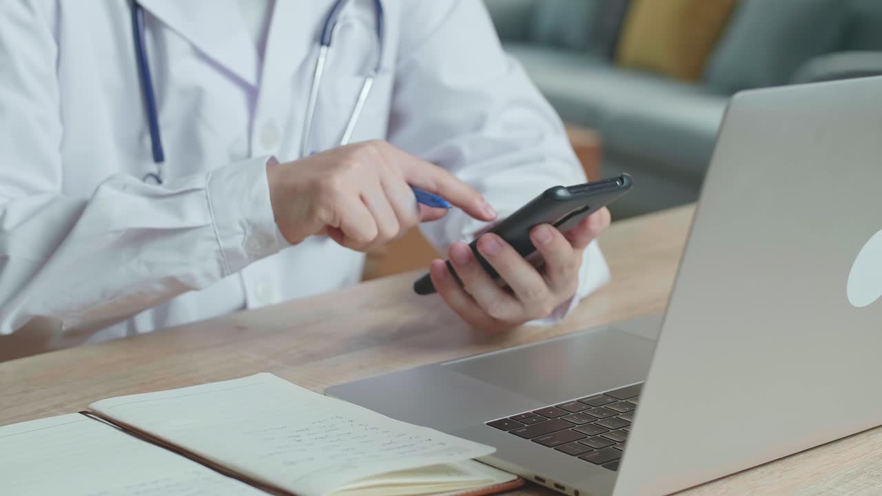 Man Doctor Use Mobile Phone And Write On Note Book During Work On Laptop Computer, Video In 4K