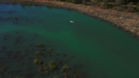 Two-Stand-Up-Paddle-Boards-at-Sylvenstein-Speicher,-scenic-mountain-valley-river-reservoir-lake-with-blue-water-in-Bavaria-Austria-alps,-flowing-down-a-beautiful-forest-along-trees