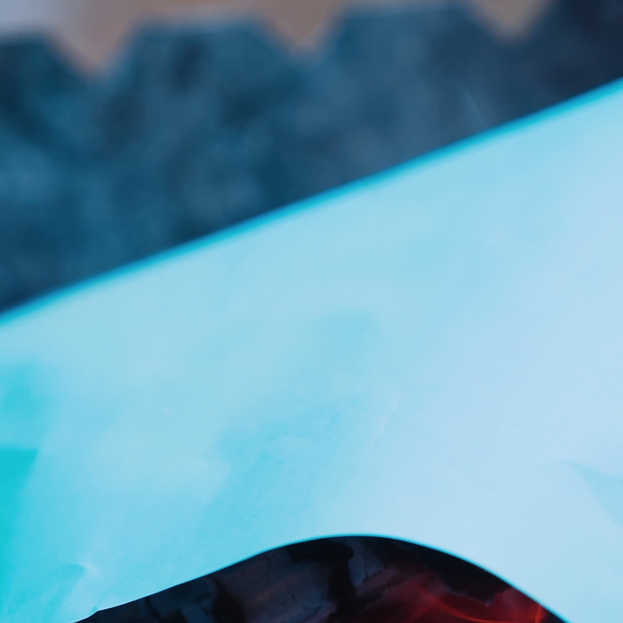 Black charcoal in bonfire close-up. White paper list falling into the fire and burning brightly. Slow motion.