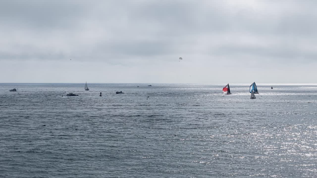 Distant sailboats drift across the hazy ocean horizon near Laguna Beach, California. The scene is softly out of focus, creating a dreamlike and painterly coastal aesthetic
