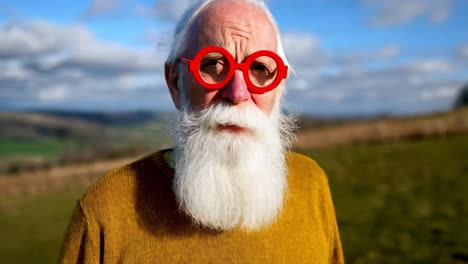 older man with red glasses in a field