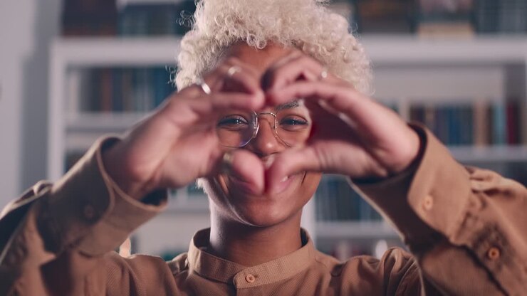 Young positive african american woman makes heart gesture with fingers