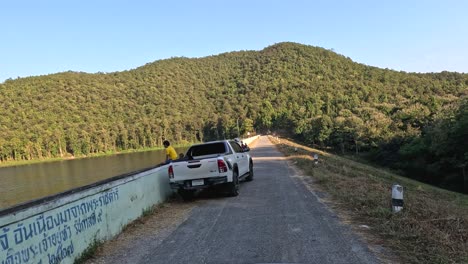 vehículo viajando por una carretera al lado de un lago
