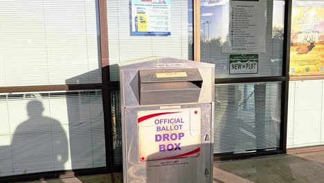 un hombre republicano deja caer una carta de votación por correo en una ranura en la cabina de votación con el cartel oficial de votación para las elecciones del gobierno democrático en la carrera presidencial