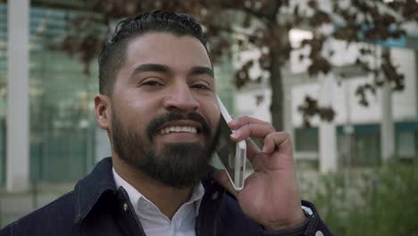 hombre barbudo alegre hablando por teléfono celular