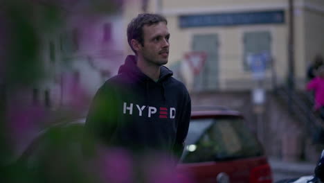 close up of a young man with dark hair walking around the european city smiling and laughing out loud during blue hour at dusk