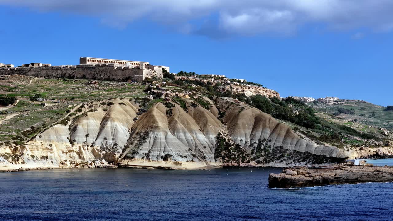 Vista panorámica aérea de los bastiones históricos del fuerte Chambray con vistas a las aguas turquesas del Mediterráneo y a las formaciones únicas de acantilados de arcilla azul en Gozo, Malta, durante un día soleado de verano.