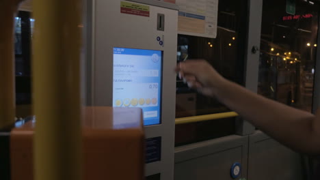 mujer usando la máquina de billetes para pagar el viaje en autobús