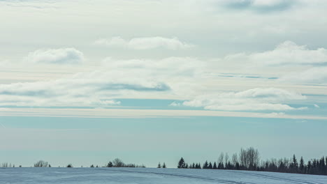 Tiro-Estático-De-Motos-De-Nieve-Pasando-En-Timelapse-Sobre-Paisaje-Rural-De-Invierno-Frío-En-Un-Día-Nublado