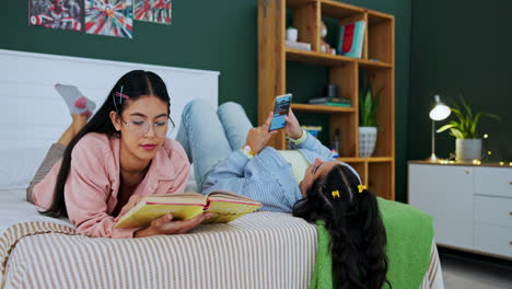 two teenage girls relaxing and reading in bedroom