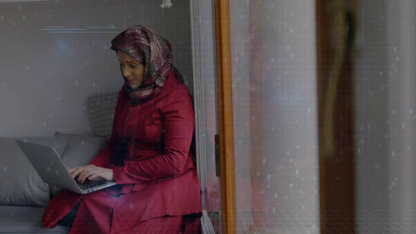 woman wearing hijab taping quickly on laptop in her room with binary codes