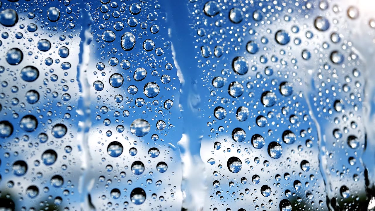 Goccioline d'acqua su superficie di vetro con sfondo di cielo blu
