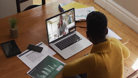 african american female teacher having a video call with male college boy on laptop at home