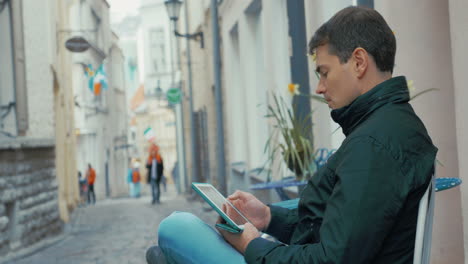 adult man with tablet computer sitting in the street