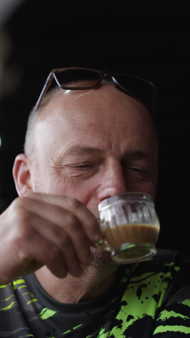 Middle-aged man tries delicious coffee in Bali, vertical close up view